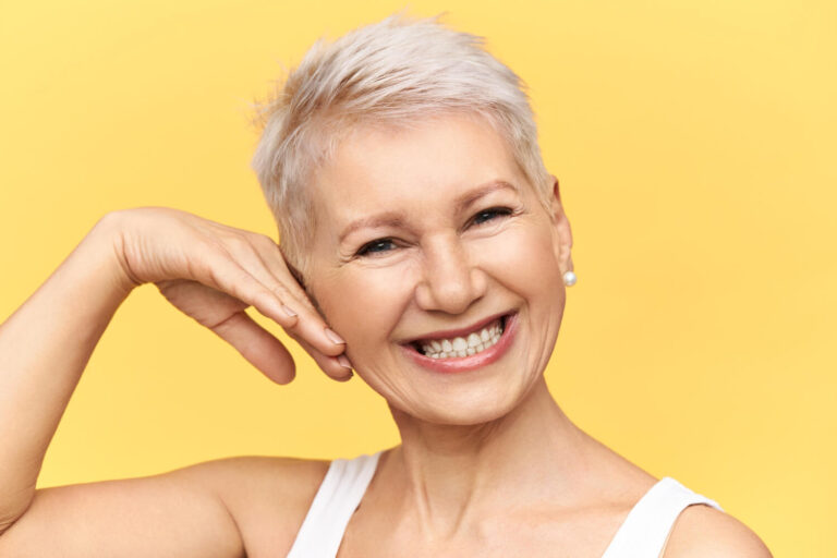 Mulher sênior sorrindo com dentes perfeitos após prótese protocolo em Cruz Alta na Odonto Esthetic Master.