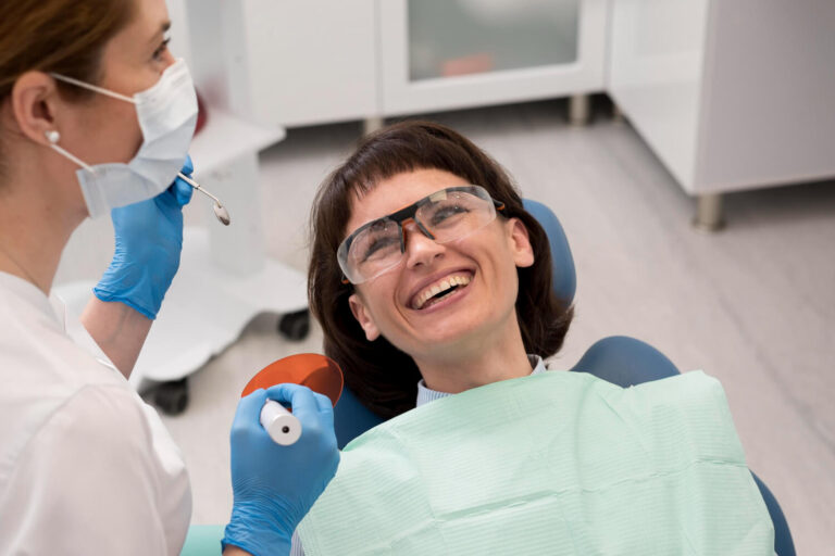 Paciente sorrindo durante clareamento dental na Odonto Esthetic Master em Cruz Alta - RS, usando óculos de proteção.