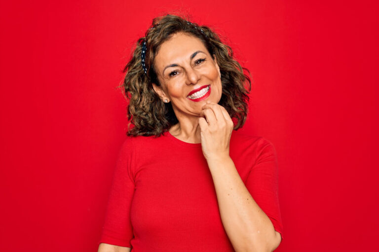 Mulher de blusa vermelha sorrindo e exibindo dentes alinhados, destacando resultados com facetas de porcelana em Cruz Alta - RS.